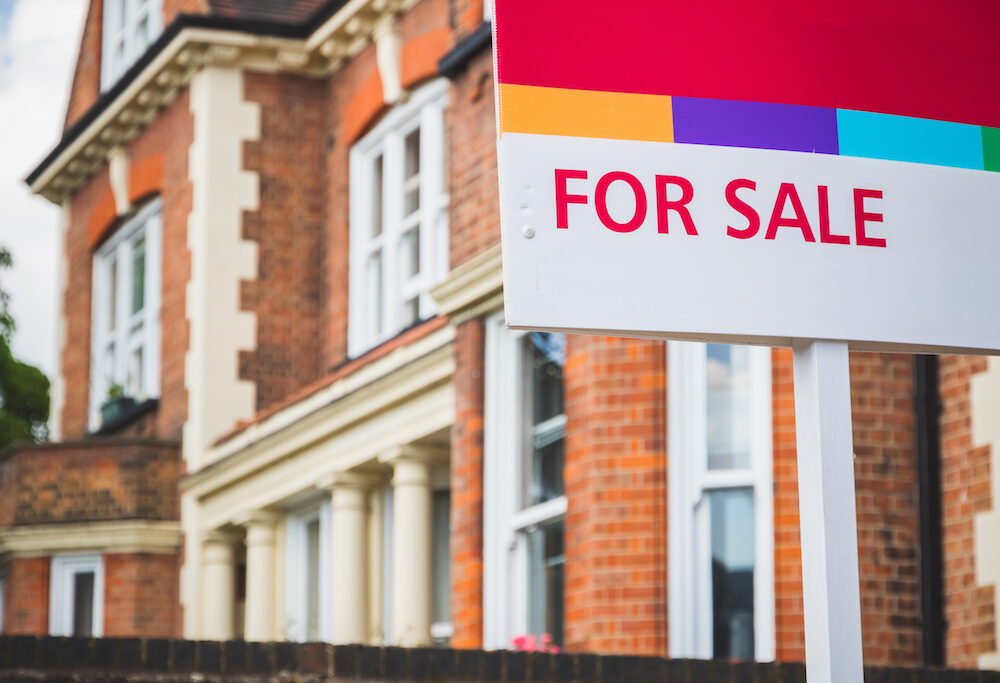 or Sale estate agent sign displayed outside a terraced house in the UK.