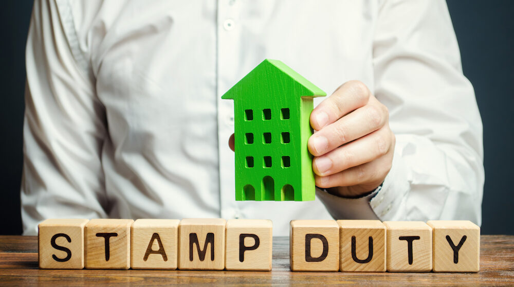 Businessman and wooden blocks with the words Stamp Duty on them.